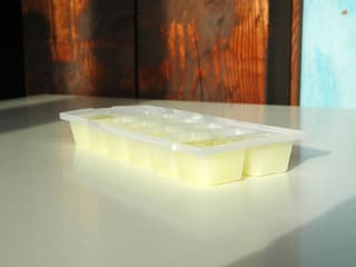 Milcheiswüfel im Eiswürfel-Behälter auf einem weissen Tisch.