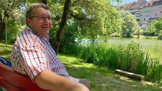 Hans Schmid sitzt auf einer roten Holzbank am Wiler Weiher.