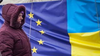 Eine Frau vor den Flaggen der EU und der Ukraine.
