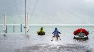Ein Kind fährt mit seinem Velo durch das Wasser am Ägerisee. Ein Kind fährt mit seinem Velo durch das Wasser am Ägerisee.