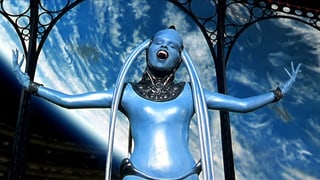 Eine Frau in blauem Kostüm singt und hält die Arme in die Luft.