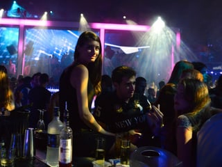 Eine junge Frau steht in einem Nachtclub an einer Bar.