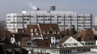 Ein Hochhaus-Gebäude hinter kleineren Häusern