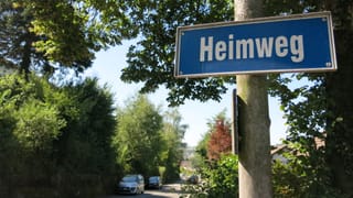 Strassenschild «Heimweg» in Köniz, Strasse gesäumt mit viel Grün. Strassenschild «Heimweg» in Köniz, Strasse gesäumt mit viel Grün.