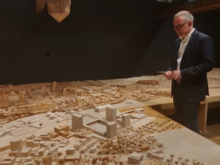 Mann mit Brille schaut auf Modell einer Stadt.