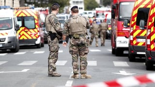 Polizisten und Rettungswagen auf einer Strasse. Davor Absperrungsband. Polizisten und Rettungswagen auf einer Strasse. Davor Absperrungsband.