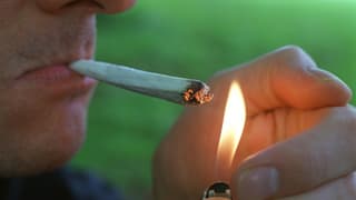 Ein Mann zündet sich einen Joint an.