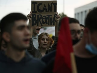 Demonstrierende in Athen – eine Frau hält ein Schild mit der Aufschrift «I can't breathe» hoch.