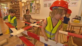 Kinder in Baustellen-Kleidung.