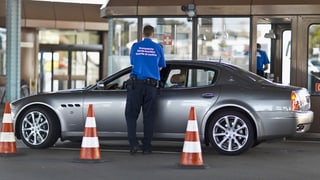 Schweizer Zollbeamter befragt einen Autofahrer in einem Sportwagen.