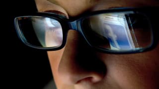 Eine Frau mit Brille, in der Brille spiegelt sich das Facebook-Logo.