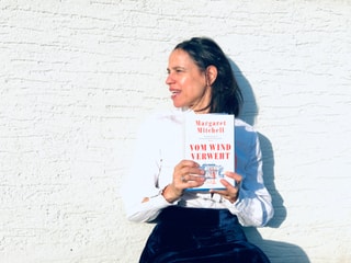 Annette König hält den Roman «Vom Wind verweht» von Margaret Mitchell in der Hand. Sie trägt im Look des 19. Jahrhunderts eine weisse Rüschenbluse und einen blauen Samtjupe. Annette König hält den Roman «Vom Wind verweht» von Margaret Mitchell in der Hand. Sie trägt im Look des 19. Jahrhunderts eine weisse Rüschenbluse und einen blauen Samtjupe.