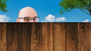 Ein Mann schaut über einen Holzzaun.