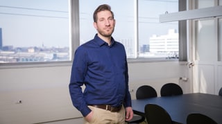 Ein ernst aussehender, junger Mann steht in einem Konferenzraum. Ein ernst aussehender, junger Mann steht in einem Konferenzraum.