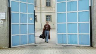 Ein Mann geht durch das leicht geöffnete Tor eines Gefängnisses.