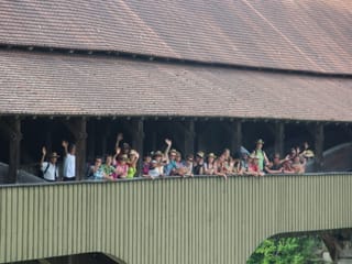 Die Wandergruppe winkt von der Holzbrücke.