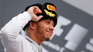 Lewis Hamilton bei der Siegerehrung mit einer Mütze auf dem Kopf.