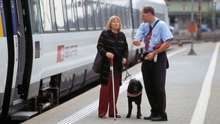 Blinde Frau und Zugführer sprechen vor Zug miteinander