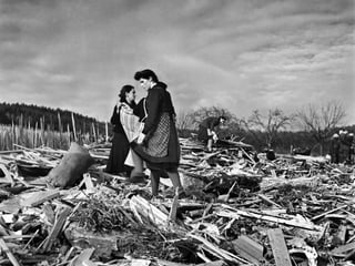 Zwei Frauen stehen nach dem Krieg auf einem Gebäudetrümmerfeld