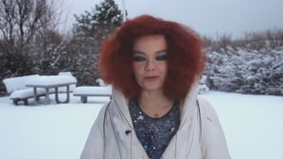 Rotes Haar, sonst fast nur Weiss: eine Frau im Schnee.