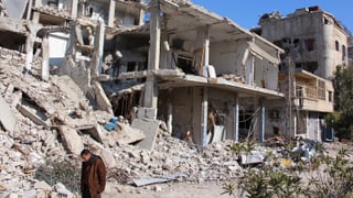 Zerbombte Häuser in einem Damaszener Vorort, davor ein Mann mit gesenktem Kopf.