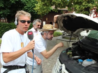 Reto Scherrer und Krispin Zimmermann vor der geöffneten Kühlerhaube des Reporterwagens.