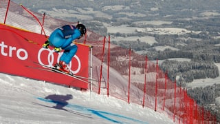 Ein Skifahrer springt in Kitzbühel über die Hauskante