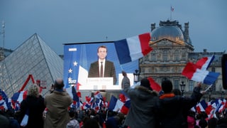Anhänger verfolgen Macrons Wahlrede auf dem Platz beim Louvre über Grossleindwand.