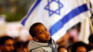 Ein Junge vor einer israelischen Fahne.