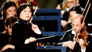 Frau mit Taktstock vor Orchester