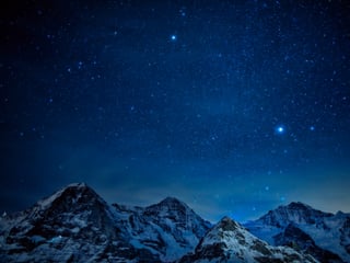 Blauer Sternenhimmel, unten Schneeberge. 