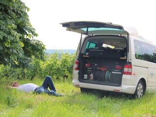 Techniker Stefan Schneider liegt im Gras hinter dem Übertragungswagen.