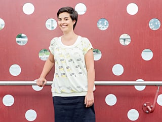 Camille Roseau steht vor einer roten Wand mit Löchern.