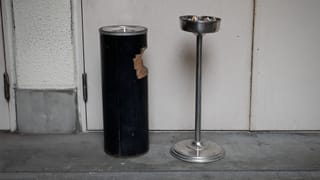 Zwei hohe Aschenbecher stehen vor einem Gebäude. Zwei hohe Aschenbecher stehen vor einem Gebäude.