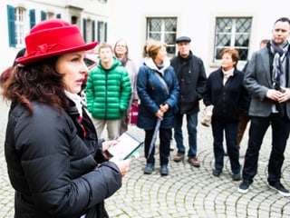 Die Führerin der Gruppe mit roten Hut. Sie steht neben den Bestatter-Fans.