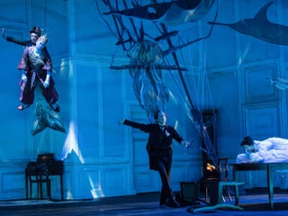 Bühne, auf welcher ein Schauspieler durch die Luft fliegt, ein weiterer auf der Bühne tanzt. Die Bühne ist in blaues Licht gehüllt und es wurde eine Art Unterwasserwelt kreiert. Bühne, auf welcher ein Schauspieler durch die Luft fliegt, ein weiterer auf der Bühne tanzt. Die Bühne ist in blaues Licht gehüllt und es wurde eine Art Unterwasserwelt kreiert.