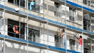 Bauarbeiter arbeiten auf einem Baugerüst an einer Fassade