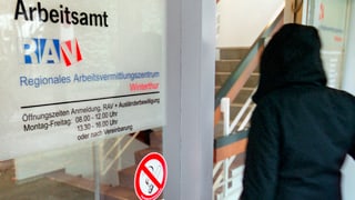 Symbolbild: Eingang zum RAV Winterthur, eine von hinten fotografierte, schwarz gekleidete Person tritt durch die Glastüre.