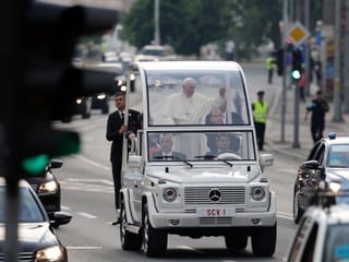 Das Papamobil mit Papst Franziskus auf einer Strasse.