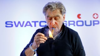 Swatch-Chef Nick Hayek zündet sich eine Zigarre an. 