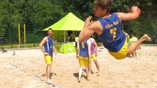 Ein Handball Spieler liegt quer in der Luft und schiesst einen Ball mit der Hand.