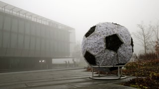 Übergrosser Fussball vor Bürogebäude im Nebel