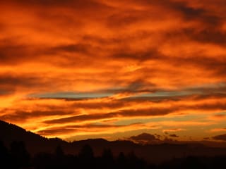Bewölkter Himmel, die Wolken leuchten orange, gelb und rot. 