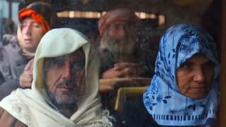 Zivilisten mit Kopftüchern sitzen in einem Bus.