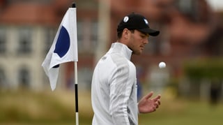 Golfer Martin Kaymer spielt auf einer Übungsrunde mit dem Golfball in der Hand.