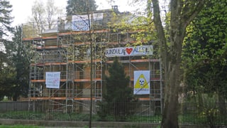 Ein Haus mit Baugerüst und bunten Transparenten.