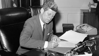  John F. Kennedy unterschreibt Dokumente.