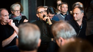 Leute sitzen auf Stühlen in einem Saal. Es wird diskutiert. Leute sitzen auf Stühlen in einem Saal. Es wird diskutiert.