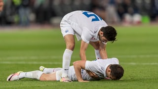 Ein FCZ-Spieler liegt am Boden, ein Kollege hilft ihm wieder auf die Beine