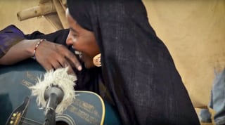 Afrikanische Frau mit Gitarre und Mikrofon.